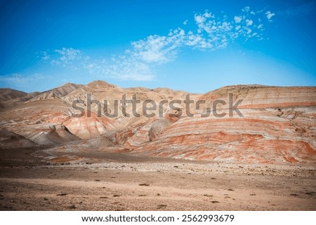Stunning view of the Candy Cane Mountains in Khizi, Azerbaijan, featuring colorful striped hills with unique cross-bedding geological formations. The vibrant layers of red, white, and beige shale rock create a breathtaking natural landscape resembling giant candy canes. A scenic road passes through the dramatic terrain, attracting tourists and nature lovers to explore this famous geological wonder. The remarkable rock formations showcase millions of years of natural erosion and sedimentary processes, making it a popular destination for geology, adventure travel, landscape photography, and outdoor exploration in Azerbaijan.