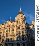 Stunning view of Casa Gallardo in Madrid, showcasing ornate Art Nouveau architecture with intricate details, balconies, and a domed roof bathed in warm sunlight against a clear blue sky.