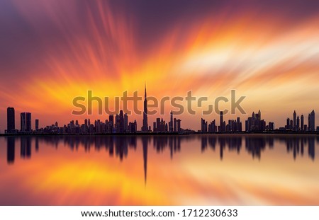 Stunning view of Dubai skyline  with warm Pastel Sunset Clouds and reflection 
