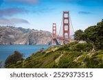 A stunning view of the Golden Gate Bridge surrounded by lush greenery and the calm waters of the San Francisco Bay.