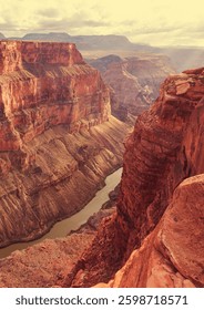 Impresionante vista del Parque Nacional del Gran Cañón al atardecer, mostrando acantilados escarpados, vastos paisajes y un cielo dorado. El sol proyecta un cálido resplandor, destacando la belleza de esta maravilla natural en Arizona