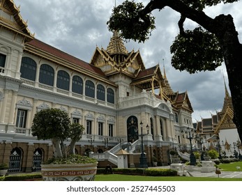 A stunning view of a historic palace with ornate architecture and lush gardens under a cloudy sky. - Powered by Shutterstock