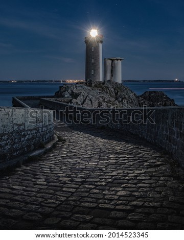 A stunning view of Le Phare du Petit Minou lighthouse at night with bright top in Plouzane, France