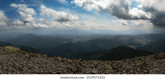 A stunning view of the mountain horizon beneath a bright blue sky dotted with clouds. The rocky foreground leads the eye toward the distant peaks, creating a feeling of vastness. - Powered by Shutterstock