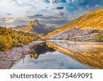 A stunning view of Panticosa village, the striking Pico de Argualas peak, and the tranquil Búbal Lake, showcasing the vibrant autumn hues of the Pyrenees, Spain.