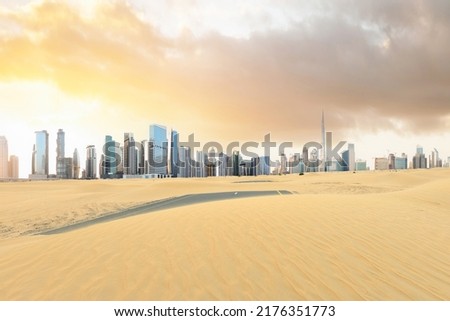Stunning view of a road covered by sand dunes with the Dubai Skyline in the distance. Dubai, United Arab Emirates.
