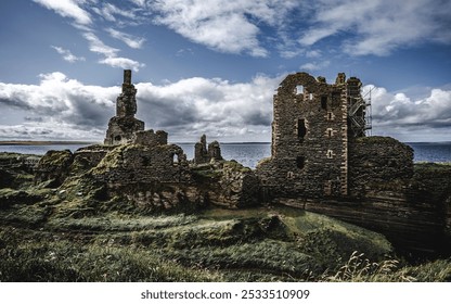 A stunning view of the ruins of an ancient castle against a dramatic sky with clouds and the sea in the background, located in a coastal region. - Powered by Shutterstock