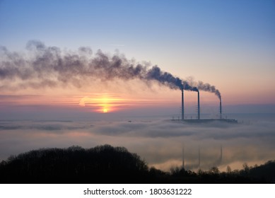 Stunning view of sky with bright rising sun at thermoelectric power plant. Thermal chimneys producing dense smoke with toxic gases into atmosphere. Concept of ecology and energy generation