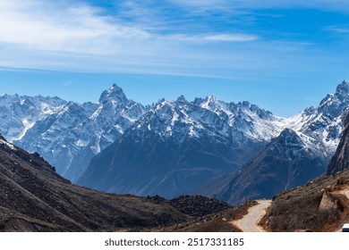 A stunning view of snow-capped mountains under a clear blue sky. Rugged peaks and a winding path create a picturesque scene, ideal for travel, adventure, nature, and outdoor themes, Sikkim, India - Powered by Shutterstock