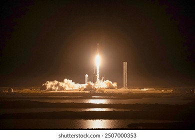 A stunning view of a space shuttle launch at night, with fiery flames and smoke billowing into the dark sky. The reflection of the launch in the calm lake. Elements of this image furnished by NASA - Powered by Shutterstock