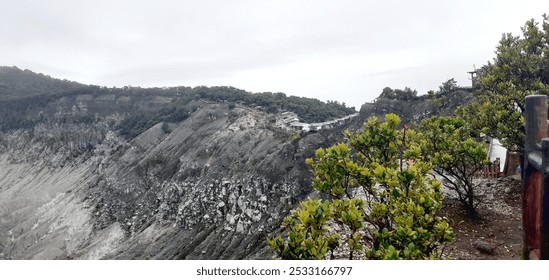 A stunning view of the steep slopes of Tangkuban Perahu volcano, featuring lush green vegetation contrasting against the rugged volcanic terrain. - Powered by Shutterstock