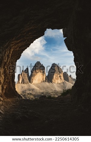 Stunning view of the Three Peaks of Lavaredo, (Tre cime di Lavaredo) during a beautiful sunset framed by a cave. The Three Peaks of Lavaredo are the undisputed symbol of the Dolomites, Italy.	