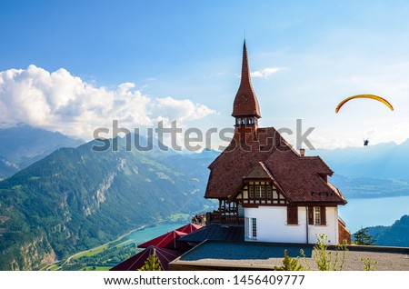 Stunning view of the top of Harder Kulm in Interlaken, Switzerland photographed in summer with paragliders flying around. Hilly Alpine landscape and Lake Thun in background. Paragliding, sunset