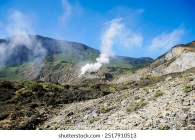 A stunning view of a volcanic landscape featuring rocky terrain and lush greenery The mountains rise majestically against a clear blue sky, showcasing the raw beauty and geological diversity of nature - Powered by Shutterstock