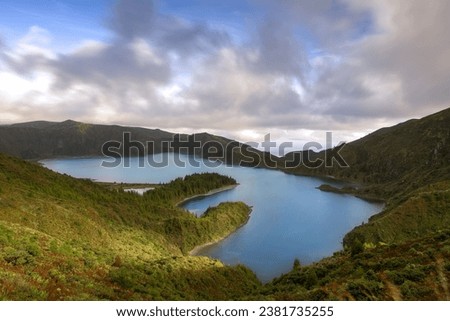 A stunning vista featuring the picturesque Lagoa do Fogo lake, nestled between dramatic mountain peaks