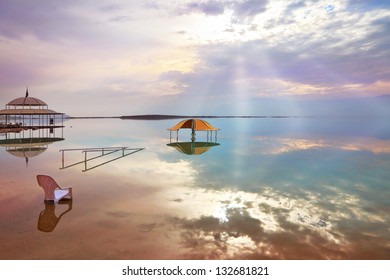 A Stunning Visual Effect On The Dead Sea. The Picturesque Gazebo For Bathers And Sun Rays Are Reflected In A Smooth Sea Surface.