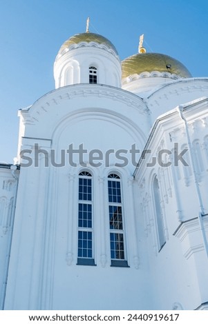 A stunning white building with two majestic gold domes atop, creating a symmetrical facade against the sky. The chapel features arch windows and intricate details, making it a holy place
