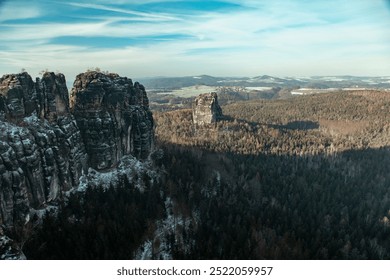 Stunning winter landscape of the Badlands in Swiss Saxony showcasing majestic cliffs and a serene forest under a clear blue sky - Powered by Shutterstock