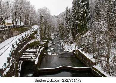 A stunning winter scene featuring a mountain river flowing through a rocky landscape, with a charming bridge crossing over the water. The snowy surroundings and ice formations create a picturesque - Powered by Shutterstock