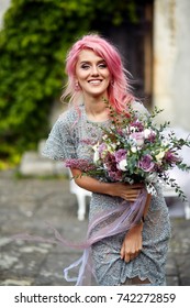 Stunning woman with pink hair stands with large wedding bouquet