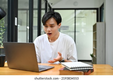 Stunning Young Asian Male College Student Or Freelancer Looking At Laptop Screen. Getting A Job Offer Email, Winning Lottery, Getting Job Promotion.