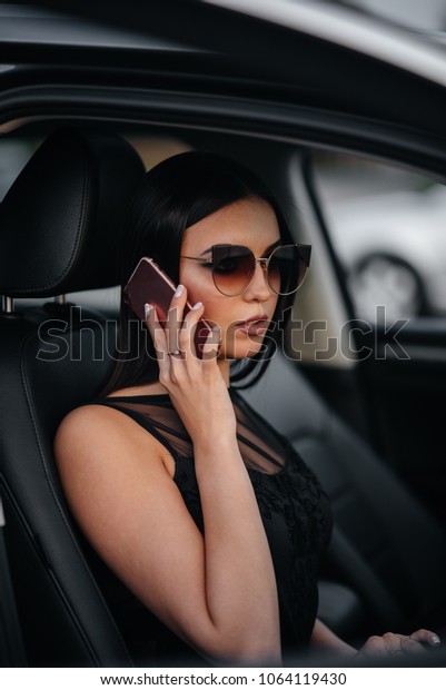 A stunningly beautiful business\
brunette talking on the phone in the car. Business.\
Fashion.