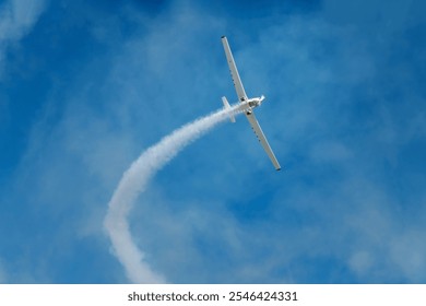 Stunt aerobatic plane performing loop in blue sky with smoke trail. Concept of speed, difficulty, precision, risk, challenge - Powered by Shutterstock