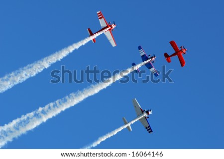 Stunt aircraft flying in formation against bright blue sky at air show performance