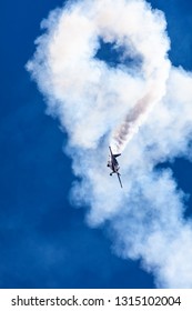 Stunt plane in a high speed nose dive at Avalon air show against a clear blue sky with smoke trail - Shutterstock ID 1315102004