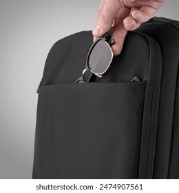 Sturdy black backpack designed with multiple zippered compartments and adjustable straps against grey background. Concept of  convenient stylish accessory for business trips and travel