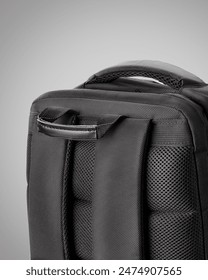 Sturdy black backpack designed with multiple zippered compartments and adjustable straps against grey background. Concept of  convenient stylish accessory for business trips and travel