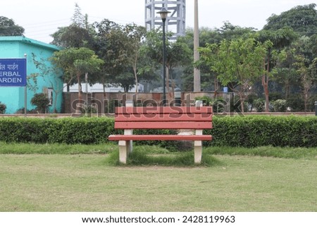 A sturdy, cemented public park chair offers comfort and relaxation amidst lush greenery. Weather-resistant and inviting, it provides a tranquil seating space for nature enthusiasts and leisure see