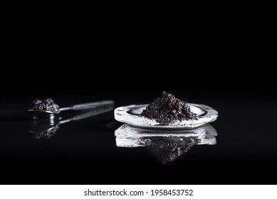 
Sturgeon black caviar in a spoon and on ice reflected in black background. Luxury delicatessen food