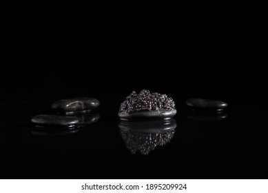 
Sturgeon caviar on black stone with reflection. Delicatessen food on black background