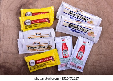 Sturtevant, Wisconsin / USA - October 2, 2019: Various single serve packets of Heinz products including ketchup mayo and yellow mustard on a cherry wood countertop. 
