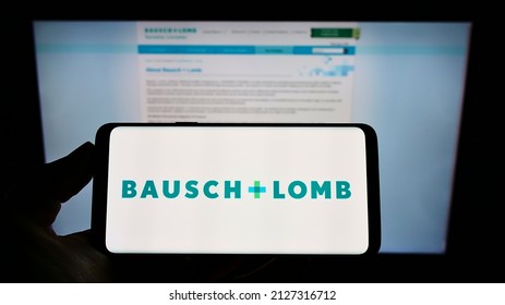 Stuttgart, Germany - 01-15-2022: Person holding smartphone with logo of Canadian eye health company Bausch + Lomb on screen in front of business web page. Focus on phone display. Unmodified photo.