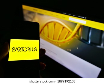 Stuttgart, Germany - 01-19-2021: Person holding cellphone with company logo of German pharmaceutical and laboratory equipment supplier Sartorius AG. Focus on smartphone screen. Unmodified photo.
