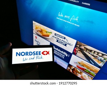 Stuttgart, Germany - 01-30-2021: Person holding smartphone with logo of German fast-food restaurant chain Nordsee GmbH on display in front of business website. Focus on phone screen. Unmodified photo.