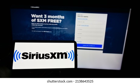 Stuttgart, Germany - 02-13-2022: Person holding cellphon with logo of American broadcasting company Sirius XM Holdings Inc. on screen in front of webpage. Focus on phone display. Unmodified photo.