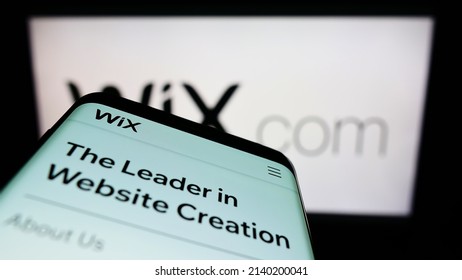 Stuttgart, Germany - 03-01-2022: Mobile phone with webpage of Israeli software company Wix.com Ltd. on screen in front of business logo. Focus on top-left of phone display. Unmodified photo.