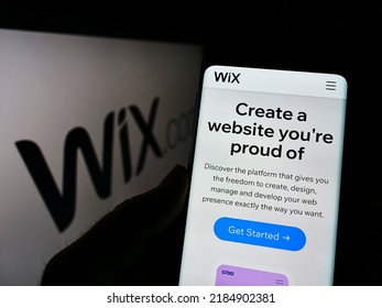 Stuttgart, Germany - 03-01-2022: Person holding cellphone with website of Israeli software company Wix.com Ltd. on screen in front of logo. Focus on center of phone display. Unmodified photo.