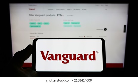 Stuttgart, Germany - 03-12-2022: Person holding mobile phone with logo of American financial company The Vanguard Group Inc. on screen in front of webpage. Focus on phone display. Unmodified photo.