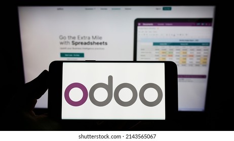 Stuttgart, Germany - 03-29-2022: Person holding mobile phone with logo of French software company Odoo SA on screen in front of business web page. Focus on phone display. Unmodified photo.