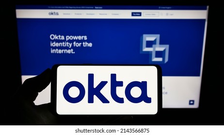 Stuttgart, Germany - 03-29-2022: Person holding smartphone with logo of US identity management company Okta Inc. on screen in front of website. Focus on phone display. Unmodified photo.