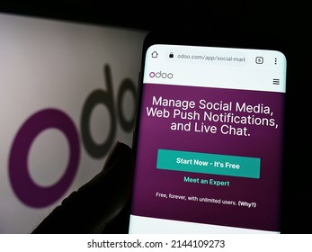 Stuttgart, Germany - 03-29-2022: Person holding smartphone with webpage of French software company Odoo SA on screen in front of business logo. Focus on center of phone display. Unmodified photo.