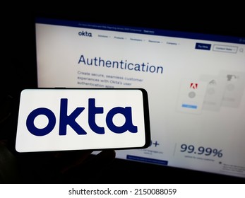 Stuttgart, Germany - 03-29-2022: Person holding cellphone with logo of US identity management company Okta Inc. on screen in front of business webpage. Focus on phone display. Unmodified photo.