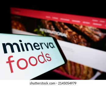 Stuttgart, Germany - 03-30-2022: Cellphone with logo of Brazilian foods company Minerva S.A. on screen in front of business website. Focus on left of phone display. Unmodified photo.