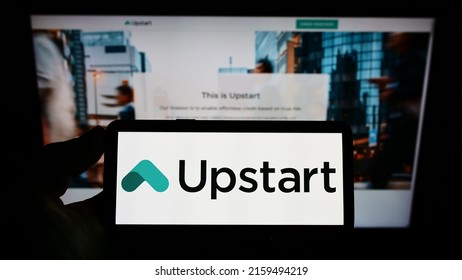 Stuttgart, Germany - 05-15-2022: Person holding cellphone with logo of US fintech company Upstart Network Inc. on screen in front of business webpage. Focus on phone display. Unmodified photo.