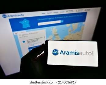 Stuttgart, Germany - 05-21-2021: Person Holding Mobile Phone With Logo Of French Online Car Dealer Aramis SAS (Aramisauto) On Screen In Front Of Web Page. Focus On Cellphone Display. Unmodified Photo.