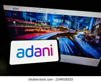 Stuttgart, Germany - 05-23-2021: Person Holding Mobile Phone With Logo Of Indian Conglomerate Adani Group On Screen In Front Of Business Web Page. Focus On Phone Display. Unmodified Photo.